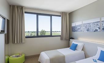 a hotel room with two twin beds and a large window , providing a view of the outdoors at B&B Hotel Bologna