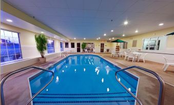 an indoor swimming pool with blue water , surrounded by white walls and filled with water , creating a serene atmosphere at Country Inn & Suites by Radisson, Rock Falls, IL