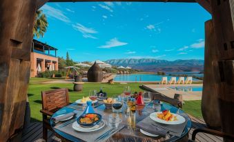 a table with plates of food and wine glasses is set up outside overlooking a pool and mountains at Widiane Resort