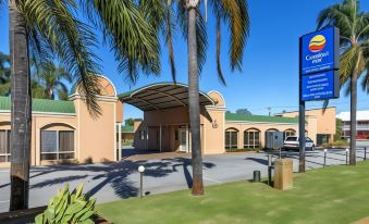 a hotel with a covered entrance and palm trees , under a clear blue sky , near a green parking lot at Ingot Hotel Perth, Ascend Hotel Collection