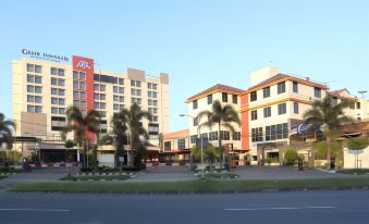 a large building with a red sign is next to a white building with palm trees at Grand Pasundan Convention Hotel
