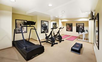 a well - equipped home gym with various exercise equipment , including treadmills and exercise bikes , under a large window at Clarion Hotel Bergen