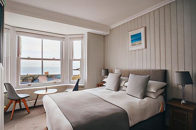 a large bed with white linens is in a room with a window overlooking the ocean at The Bay Hotel
