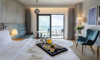 a hotel room with a large bed , a tray with food and drinks on it , and a balcony overlooking the ocean at Radisson Blu Hotel Trabzon