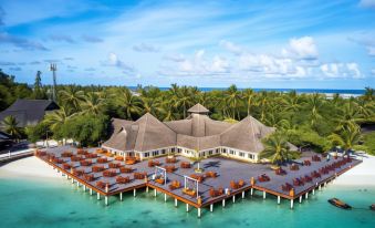 a resort on stilts over the water , with several tables and chairs set up for people to enjoy the view at Sun Siyam Olhuveli