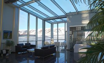 a modern living room with a glass wall and floor to ceiling windows overlooking the ocean at Hotel Selfoss