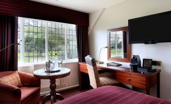 a hotel room with a comfortable bed , a tv , and a desk with a laptop at Macdonald Craxton Wood Hotel