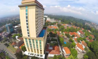 an aerial view of a tall building with a pool on its roof , surrounded by other buildings and trees at Swiss-Belhotel Bogor
