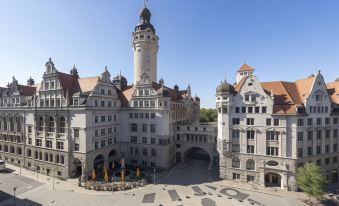 a large , historic building with a tower and several flags is shown from an aerial perspective at NH Leipzig Zentrum