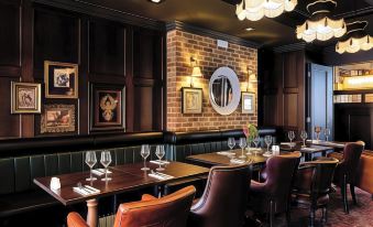 a restaurant with wooden tables and chairs , brick walls , and a large mirror on the wall at Caledonian Hotel