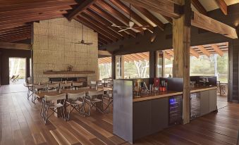 a modern restaurant with wooden flooring , large windows , and an open kitchen area with chairs and tables at Mt Mulligan Lodge