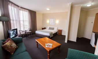 a hotel room with a king - sized bed , a couch , a chair , and a tv . also a dining table in the room at Barkly Motorlodge