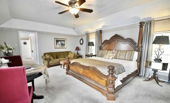 a large bedroom with a wooden bed , a couch , and a ceiling fan , all decorated in white and brown tones at Sassafras Inn