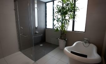 a modern bathroom with a white bathtub , green plant , and large windows overlooking the outdoors at Pinetree Hotel