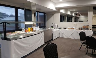 a room with a dining table set up for breakfast , featuring a variety of food and drinks at Burnie Central Townhouse Hotel