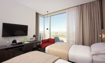a hotel room with two beds , a desk , and a window offering a view of the city at Holiday Inn Algiers - Cheraga Tower