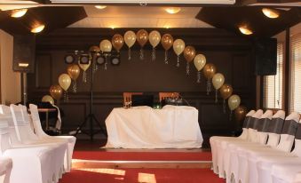 a wedding reception with chairs arranged in a semicircle around a table , decorated with balloons at Birch Hotel