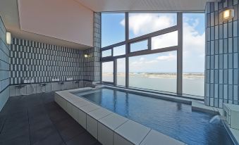 a large indoor swimming pool with a view of the ocean through a large window at Yamadaya