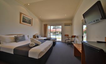 a hotel room with two beds , a television , and a window that opens to the balcony at Emerald Explorers Inn