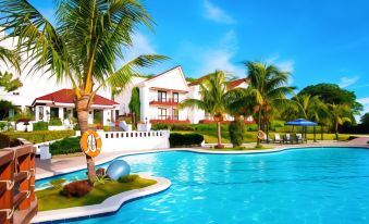 a resort with a large pool surrounded by palm trees and a house in the background at Thunderbird Resorts - Rizal