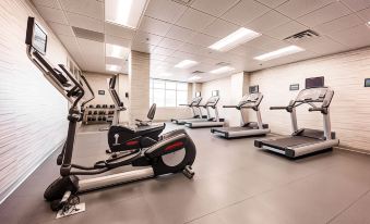 a large , well - lit gym with various exercise equipment , including treadmills , stationary bikes , and weight machines at Courtyard Rome Riverwalk