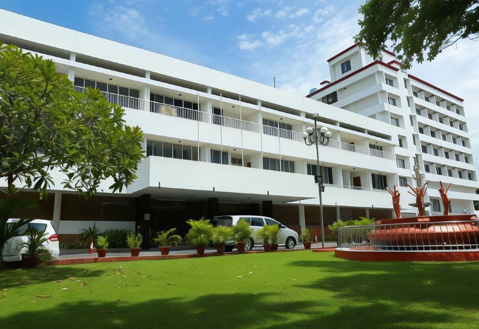 a large white building with a parking lot in front of it and several potted plants at Casino Hotels Ltd