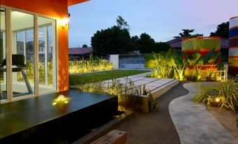 a modern house with a garden area featuring a bench and potted plants , set against the backdrop of a dark blue building at Ppt Muar Hotel