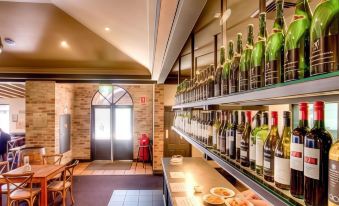 a wine cellar with various bottles of wine displayed on shelves and tables , as well as a dining area with chairs at Potters Apartments