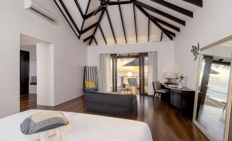 a modern bedroom with wooden floors and a large bed , overlooking a balcony with a view of the ocean at Noku Maldives