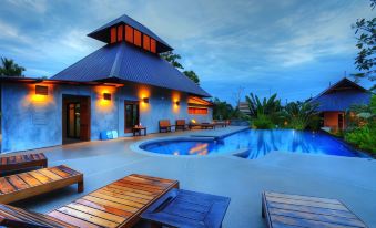 a modern , minimalist house with a blue roof and large swimming pool , surrounded by wooden lounge chairs at Chalicha Resort