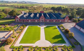 aerial view of a large red building surrounded by a green lawn , with mountains in the background at Barossa Gateway Motel