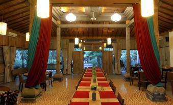 a long dining table covered with red tablecloths and surrounded by chairs in a room with wooden walls at Rumah Batu Boutique Hotel