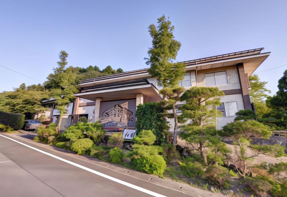 a large building with a sign on the side is surrounded by trees and bushes at Shouen