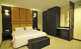 a modern hotel room with a large bed , white bedding , and black leather furniture , including a desk and cabinets at White Inn Nongkhai Hotel