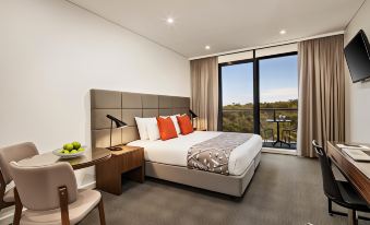 a modern bedroom with a large bed , desk , and sliding glass doors leading to a balcony at Quest Kings Park