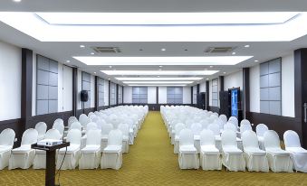 a large conference room with rows of white chairs and a yellow carpet , ready for an event at Solaris Hotel Malang