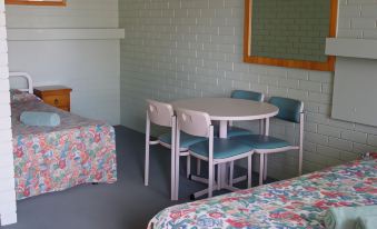 a dining table and chairs are placed in a room with a bed , nightstand , and window at Ardeanal Motel