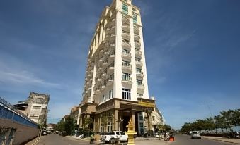 a tall building with a white facade and many windows is situated on a street corner at Lbn Asian Hotel