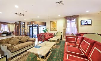 a spacious living room with multiple couches , chairs , and a dining table , as well as a television at Greenwood Hotel