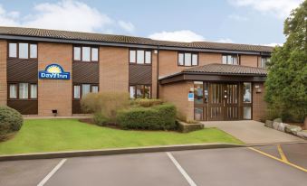 "a large building with a blue sign that says "" days inn "" is surrounded by grass and trees" at Days Inn by Wyndham Sedgemoor M5