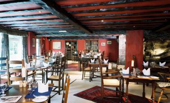 a restaurant with red walls and a wooden ceiling has several tables , chairs , and a rug at The Wild Boar