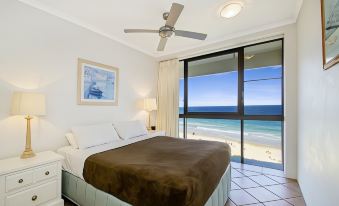 a bedroom with a large bed , ceiling fan , and sliding glass door leading to an ocean view balcony at Coolum Caprice