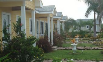 a row of small , yellow cottages surrounded by lush greenery and flowers , creating a picturesque setting at Country Cove