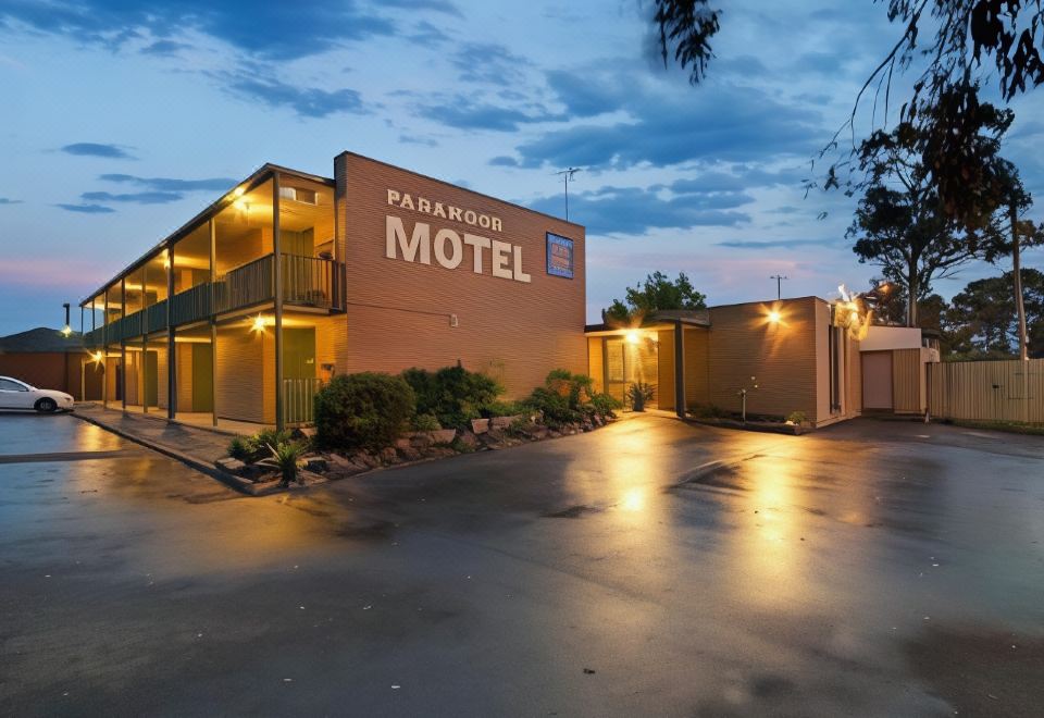 "a hotel building with the name "" pendleton motel "" lit up at night , surrounded by trees and parked cars" at Parkwood Motel and Apartments