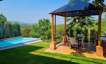 a patio area with a pool and a gazebo overlooking a grassy hillside and a pool at Kirirath Resort