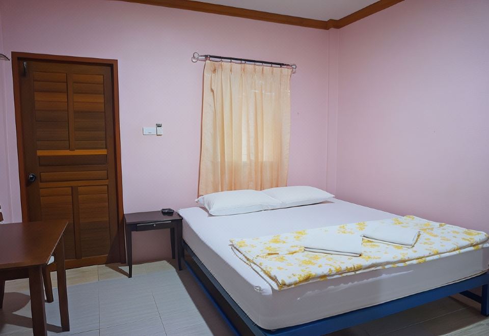 a bed with a white mattress and yellow floral sheets is in a room with pink walls at Lam-Tong Resort