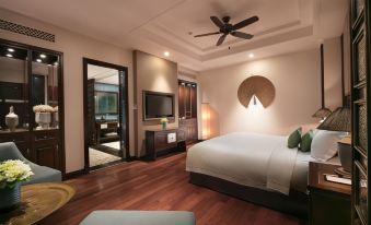 a bedroom with a large bed , wooden floors , and a fan hanging from the ceiling at Ninh Binh Hidden Charm Hotel & Resort