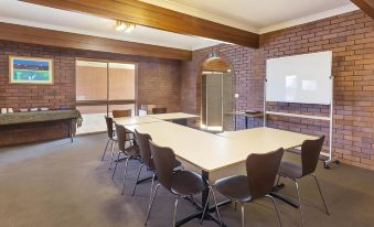 a conference room with a long table and chairs , a whiteboard , and a projector screen at Blue Shades Motel