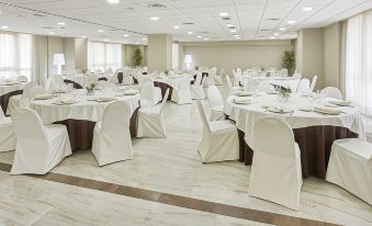 a large banquet hall with white tablecloths and chairs , creating a formal dining experience for guests at Hesperia Vigo