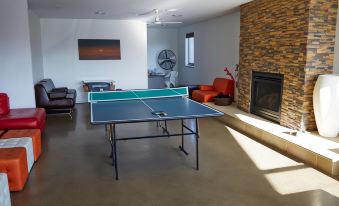 a living room with a ping pong table in the middle , surrounded by chairs and a fireplace at The Island Accommodation